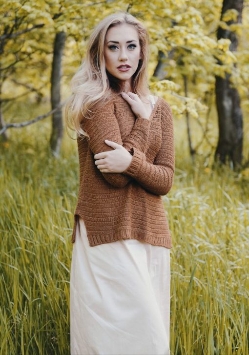 woman wearing brown sweater standing on green grass field