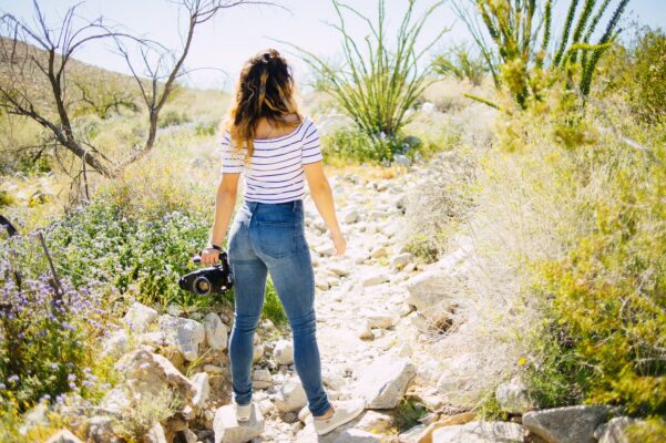 woman standing on grey rock facing green plants