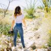 woman standing on grey rock facing green plants