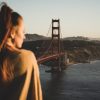 woman in brown jacket standing on bridge during daytime