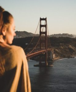 woman in brown jacket standing on bridge during daytime