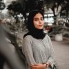 woman in gray sweater standing on road during daytime